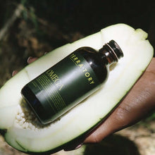 Load image into Gallery viewer, Coriander Seed Omega Body Oil displayed in a papaya half highlighting its nourishing properties.
