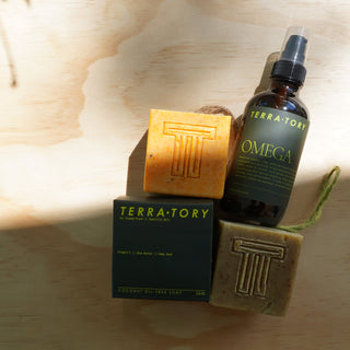 Terratory soap bars and Omega serum on a wooden background, showcasing natural skincare products.