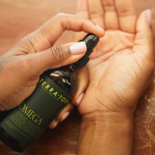 Hand holding a bottle of Terta-tory skincare product over another hand 